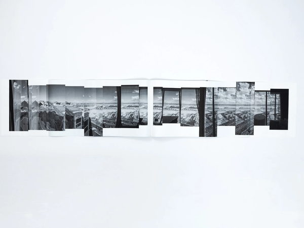 A photo book opened out into a gatefold, its fold-in panels extended across the table